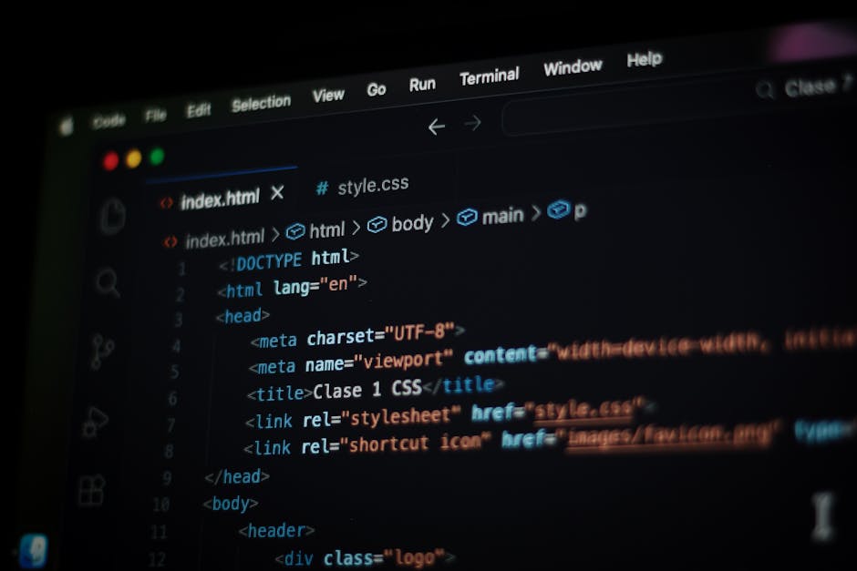 Close-up image of a computer screen displaying a code editor with HTML and CSS syntax. The visible code includes tags such as <html>, <head>, <title>, and <link>. The interface shows a dark background